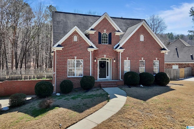 traditional home with a front yard, brick siding, and fence