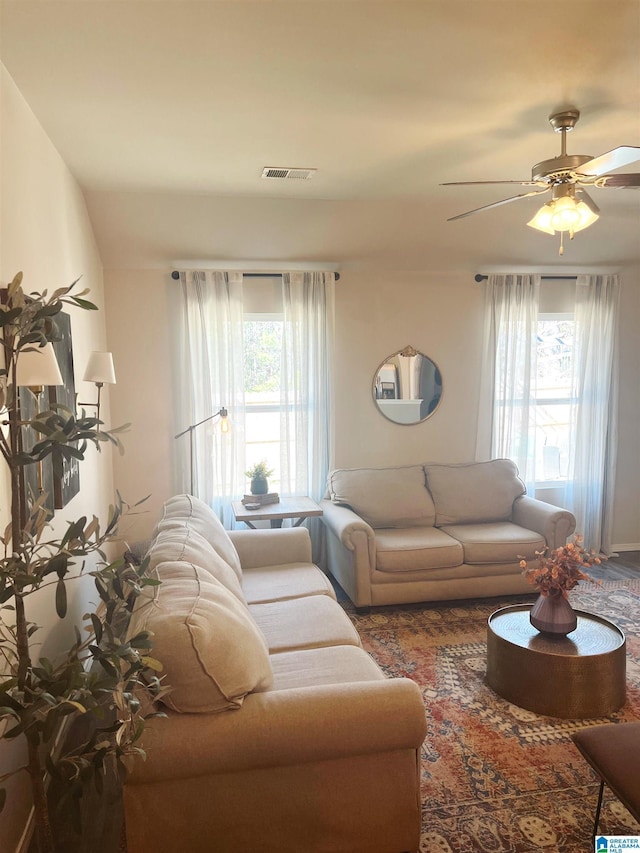 living area featuring plenty of natural light, visible vents, and ceiling fan