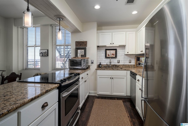 kitchen with appliances with stainless steel finishes, a sink, white cabinetry, and pendant lighting