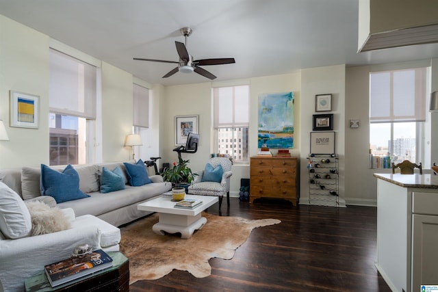 living room featuring dark wood-type flooring, a ceiling fan, and baseboards