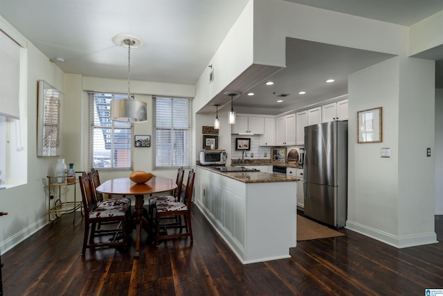 kitchen with a kitchen island with sink, white cabinets, hanging light fixtures, appliances with stainless steel finishes, and dark stone counters