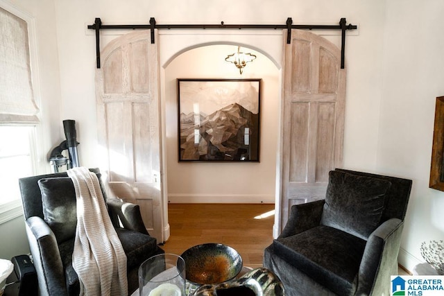 living area with a barn door, wood finished floors, and baseboards