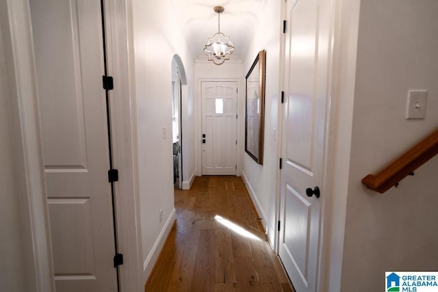 hall with baseboards, hardwood / wood-style flooring, and a notable chandelier