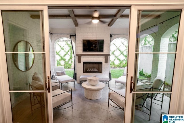 interior space with an outdoor brick fireplace, beam ceiling, and ceiling fan