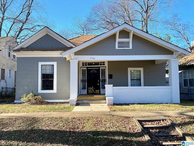 bungalow with a porch and brick siding