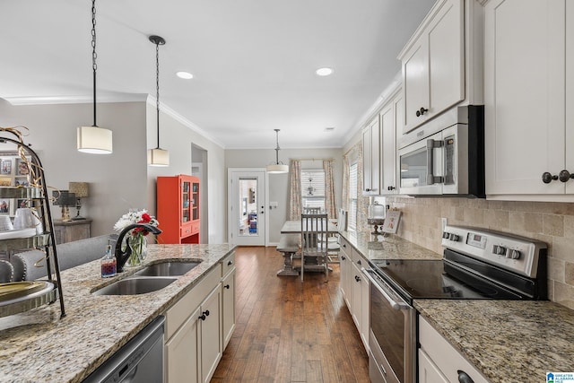 kitchen featuring appliances with stainless steel finishes, pendant lighting, white cabinets, and a sink