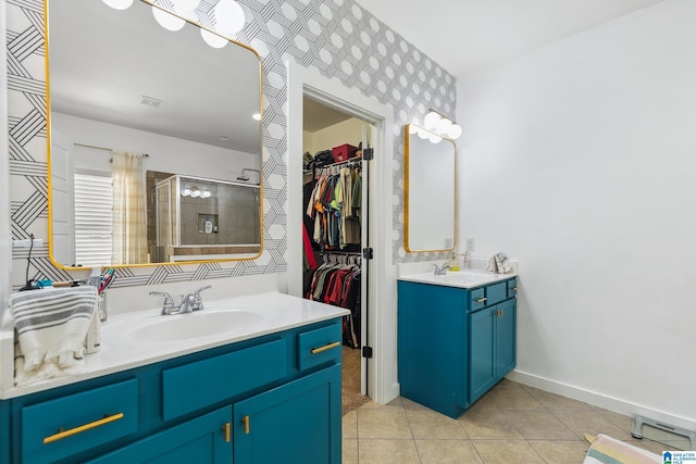 full bath featuring a stall shower, tile patterned flooring, two vanities, and a sink