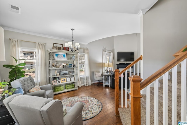 living room featuring visible vents, stairs, an inviting chandelier, dark wood finished floors, and crown molding