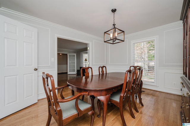 dining area featuring crown molding, light wood finished floors, and a decorative wall