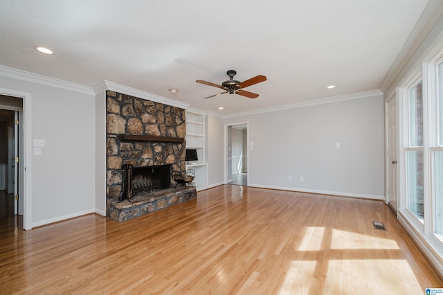 unfurnished living room featuring ornamental molding, a healthy amount of sunlight, and a stone fireplace