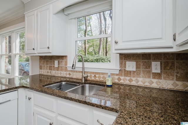 kitchen with dark stone countertops, white cabinets, and a sink