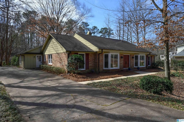 ranch-style home with concrete driveway, brick siding, and a chimney