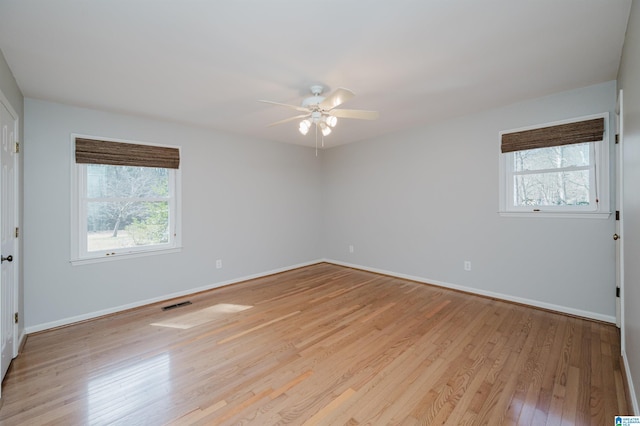 unfurnished room featuring baseboards, a wealth of natural light, visible vents, and light wood-style floors