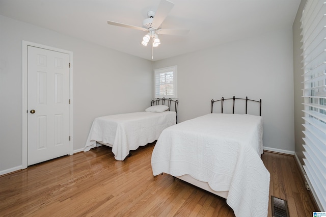 bedroom with visible vents, ceiling fan, baseboards, and wood finished floors