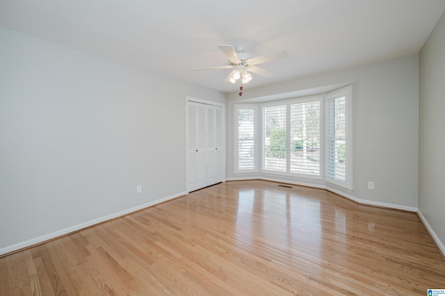 spare room with visible vents, ceiling fan, light wood-style flooring, and baseboards