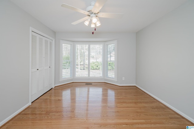 unfurnished room featuring visible vents, light wood finished floors, a ceiling fan, and baseboards