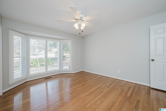 unfurnished room featuring ceiling fan, light wood-type flooring, visible vents, and baseboards