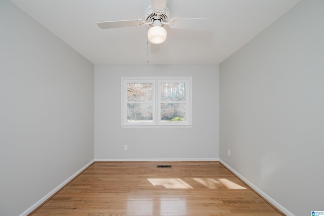 empty room with a ceiling fan, visible vents, light wood-style flooring, and baseboards