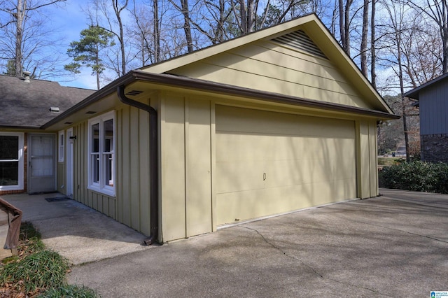 view of home's exterior featuring roof with shingles, board and batten siding, and a detached garage