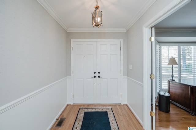 entrance foyer featuring light wood finished floors, baseboards, visible vents, and crown molding