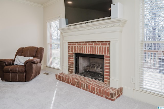 living area featuring a brick fireplace, carpet flooring, visible vents, and crown molding