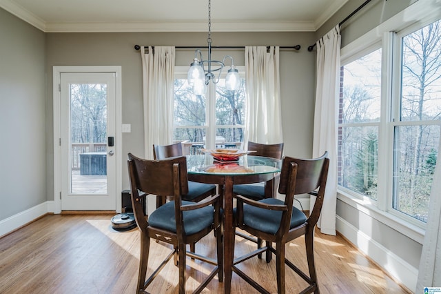 dining area with baseboards, an inviting chandelier, light wood-style flooring, and crown molding