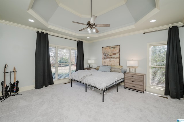 carpeted bedroom with a tray ceiling, multiple windows, recessed lighting, and crown molding