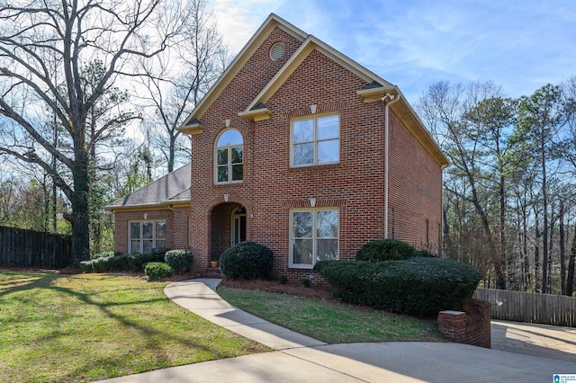 traditional-style home with fence, a front lawn, and brick siding