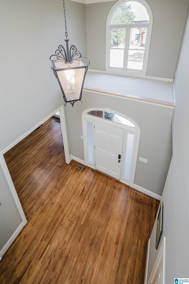 foyer with baseboards, a chandelier, and wood finished floors