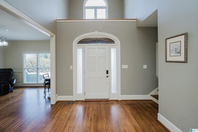 foyer featuring a high ceiling, wood finished floors, visible vents, baseboards, and stairs