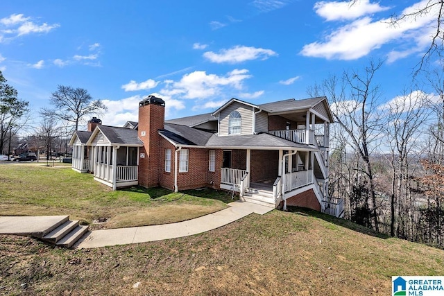 view of front of property with a sunroom, a front yard, covered porch, and brick siding