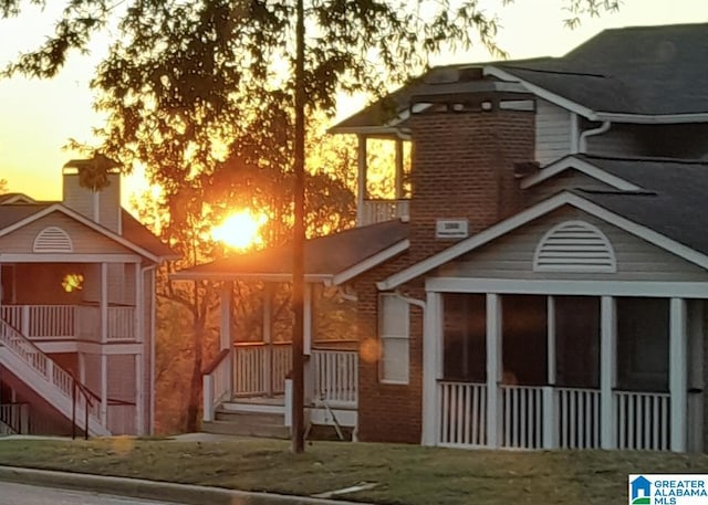 rear view of house with brick siding and a sunroom