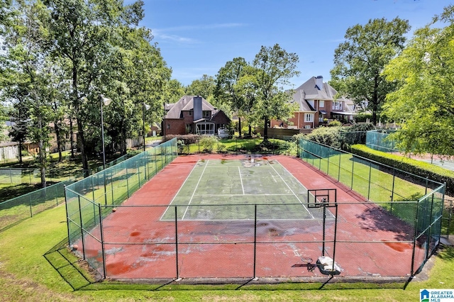 view of sport court with fence and a lawn