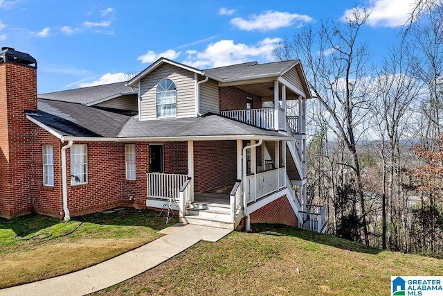 view of front facade featuring covered porch, brick siding, a front lawn, and roof with shingles