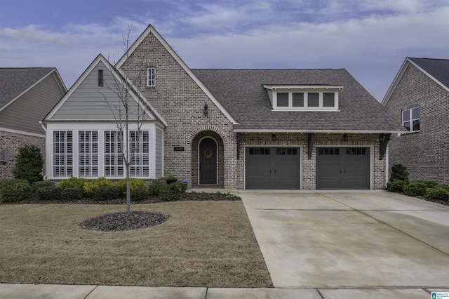 view of front of home with a shingled roof, brick siding, driveway, and a garage