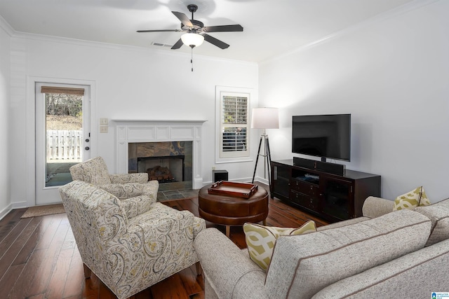 living area featuring visible vents, a ceiling fan, a tiled fireplace, dark wood-style floors, and ornamental molding