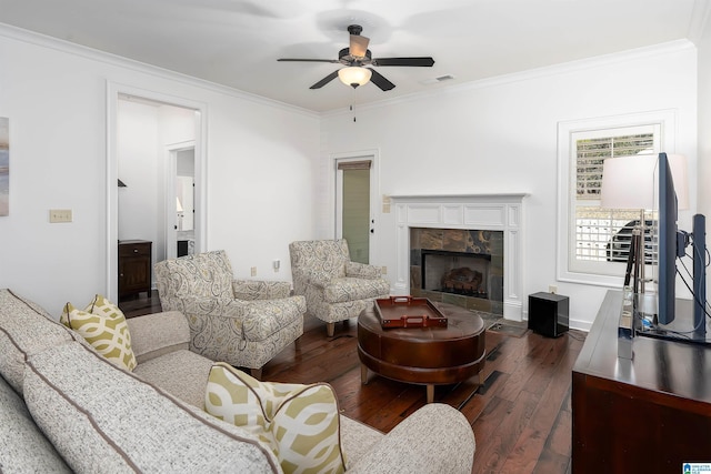 living area with a tile fireplace, visible vents, dark wood finished floors, and ornamental molding