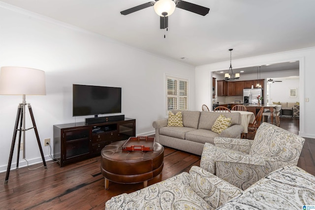 living area with ornamental molding, dark wood finished floors, baseboards, and ceiling fan