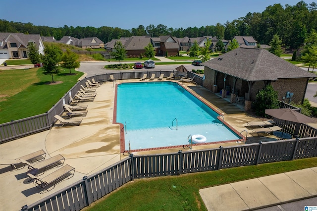 community pool with a yard, a patio area, fence, and a residential view