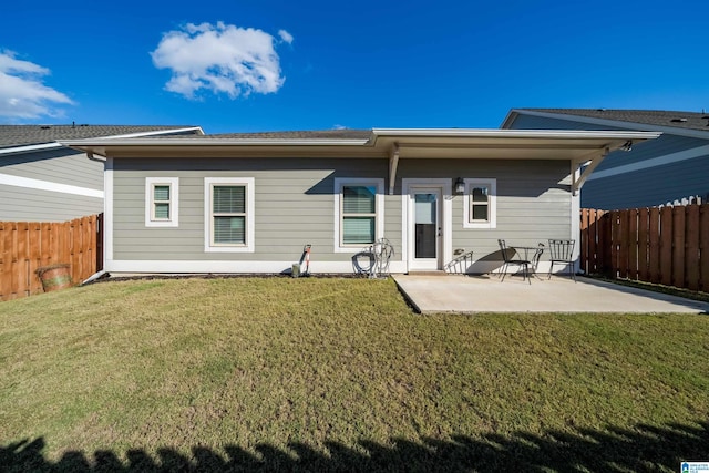 back of property with a patio area, a fenced backyard, and a lawn