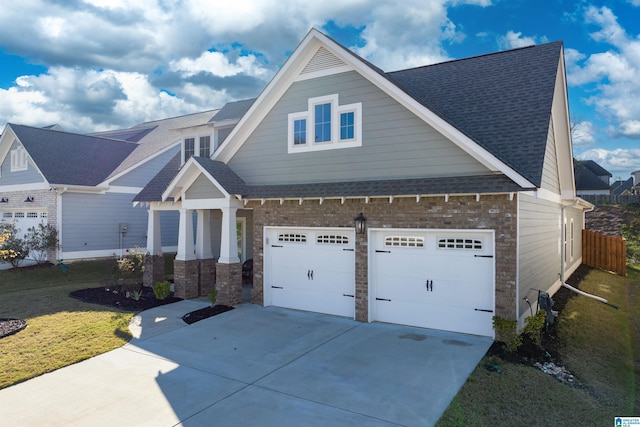 craftsman-style home with an attached garage, brick siding, driveway, roof with shingles, and a front yard