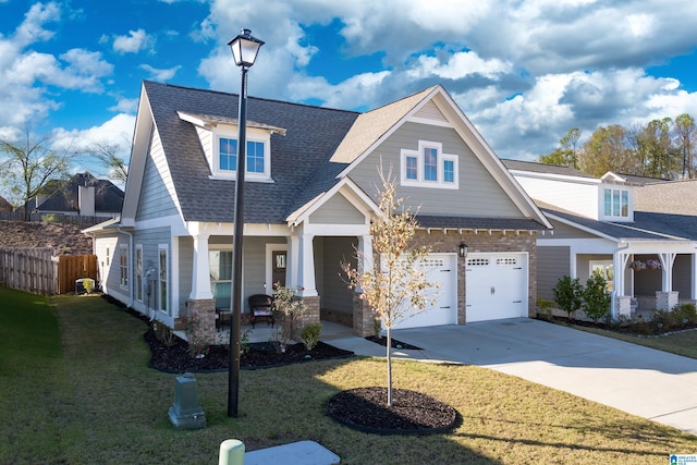 craftsman inspired home with roof with shingles, covered porch, concrete driveway, fence, and a front lawn