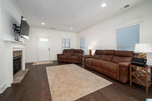 living room featuring a fireplace with raised hearth, recessed lighting, visible vents, dark wood-style floors, and crown molding