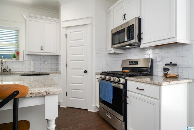 kitchen featuring light stone counters, stainless steel appliances, tasteful backsplash, dark wood-type flooring, and white cabinets