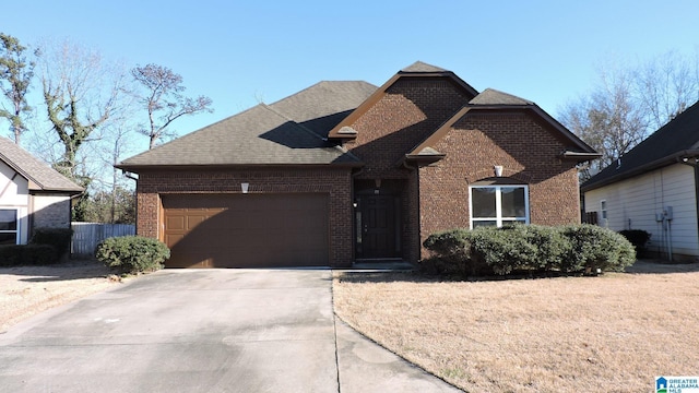 view of front of property featuring brick siding, a shingled roof, an attached garage, fence, and driveway