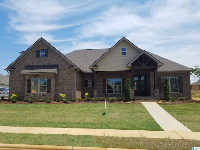 craftsman house with brick siding, roof with shingles, and a front yard