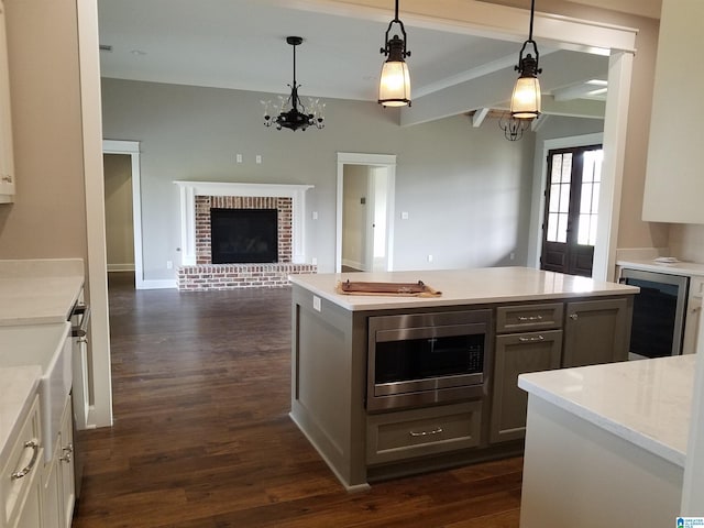 kitchen with dark wood-style floors, light countertops, stainless steel microwave, open floor plan, and a kitchen island