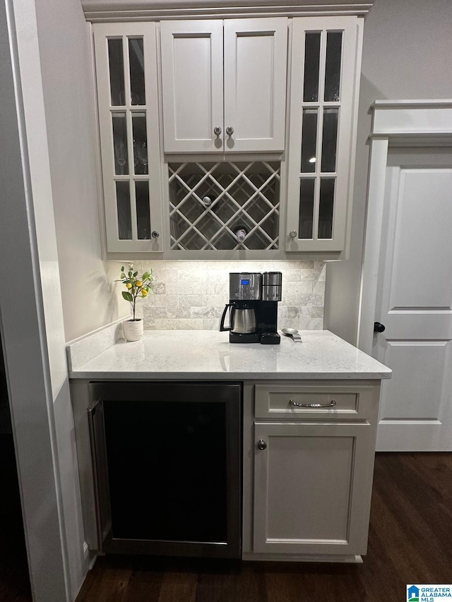 bar with a bar, dark wood-type flooring, and backsplash