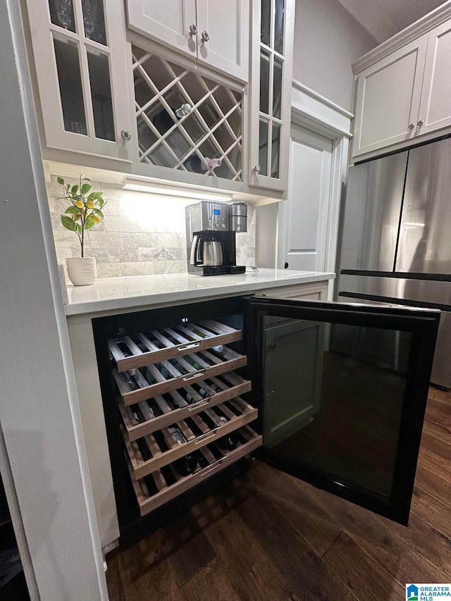 bar featuring a dry bar, decorative backsplash, dark wood-style flooring, and freestanding refrigerator