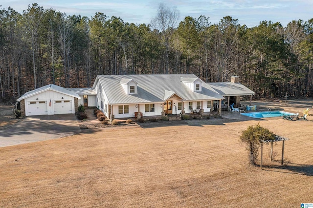 view of front of home with metal roof, a porch, and a forest view